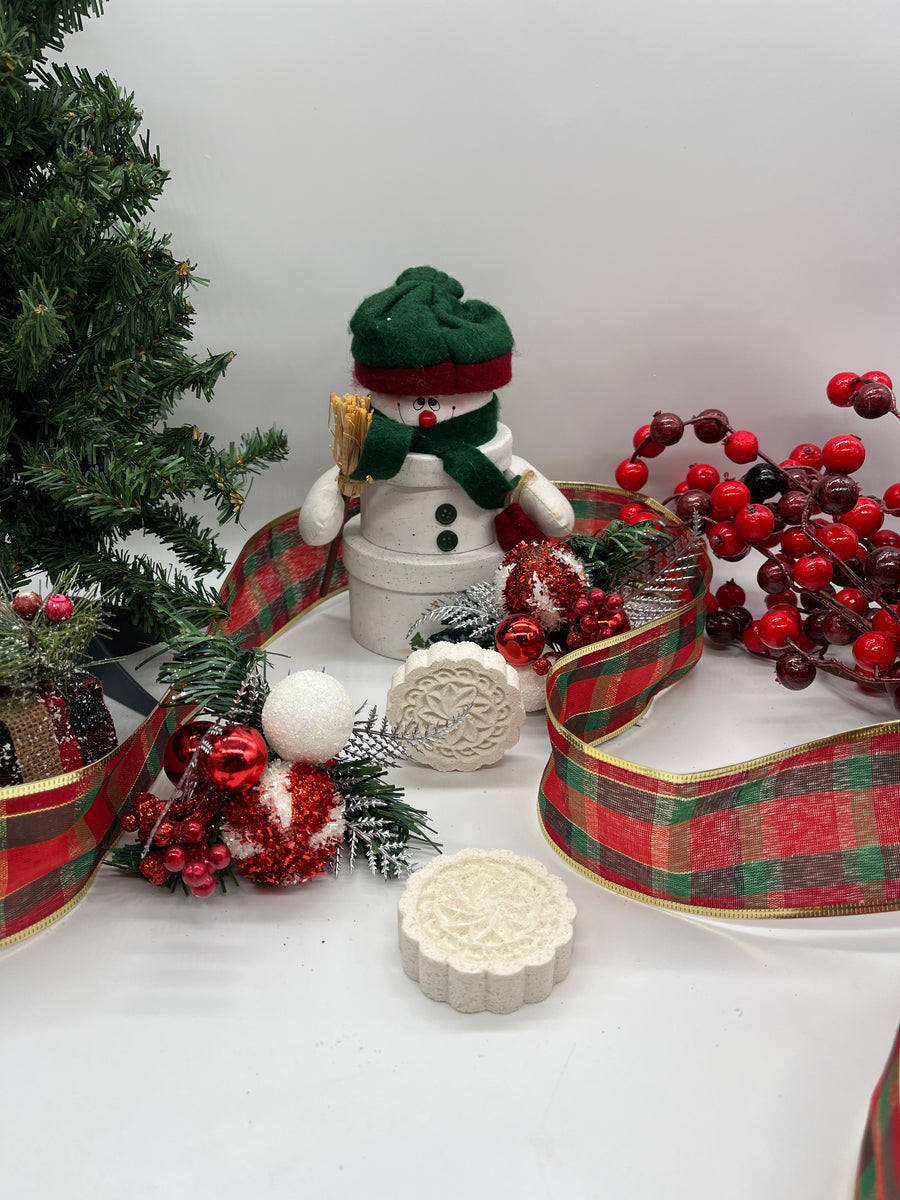 all natural christmas themed shower steamers shaped like snowmen resting on a christmas themed background